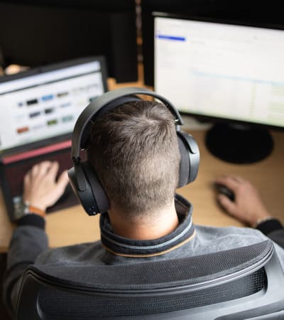illustration prestation site internet vitrine e-commerce homme devant deux ecrans d'ordinateur avec un casque'